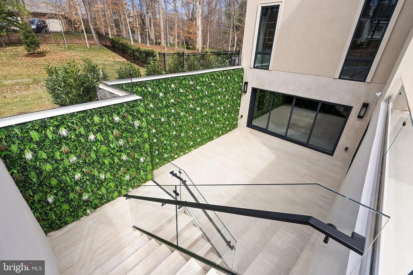 Sunken patio with vertical garden and glass stair railing at the Bethesda Custom Modern Home